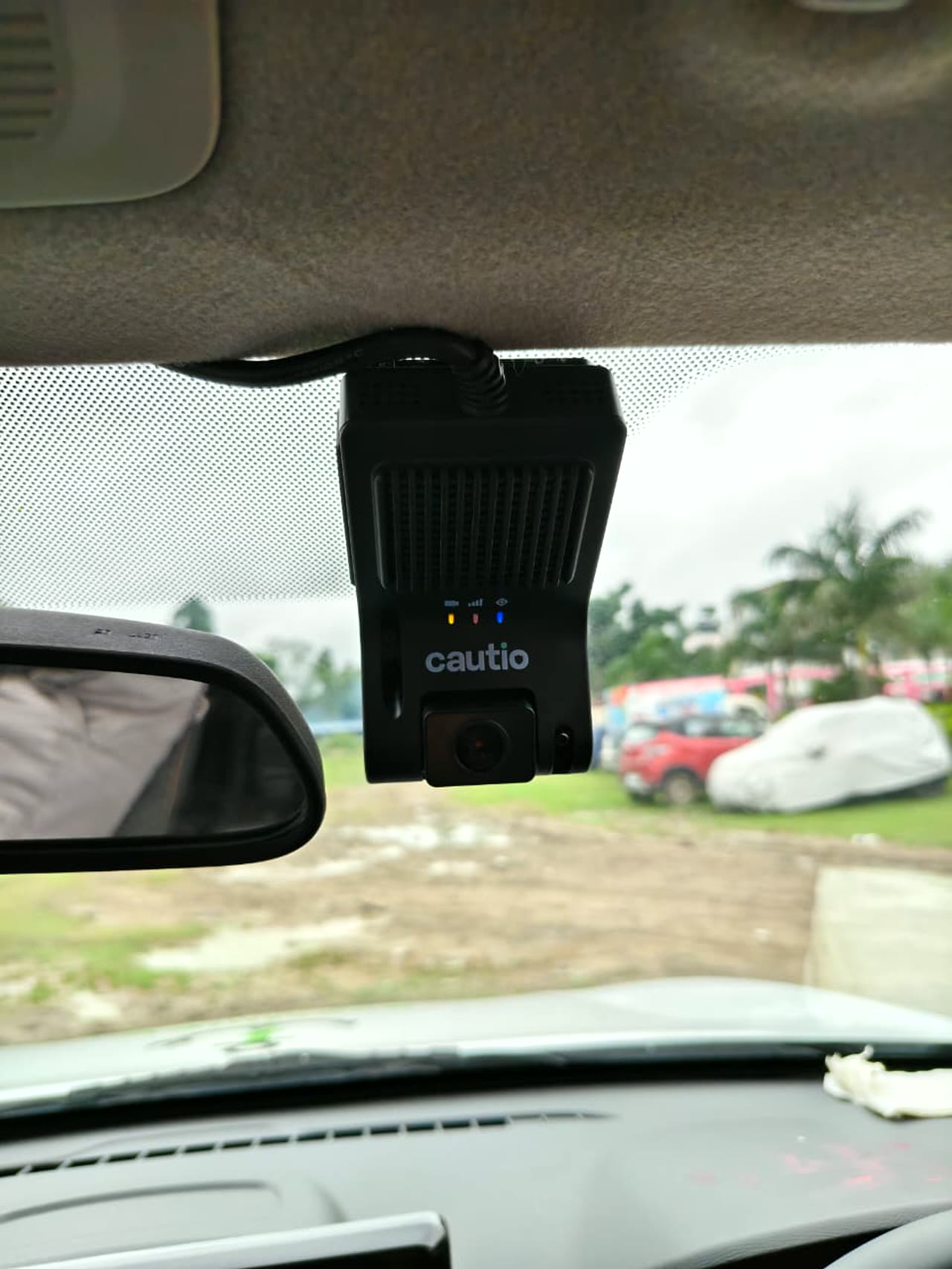 The Cautio HD dashcam unit mounted at the windshield of a SaarthiEV cab, status lights on, recording the road